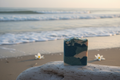 Goat milk soap bar on driftwood at the ocean's edge with water lilies and sea foam